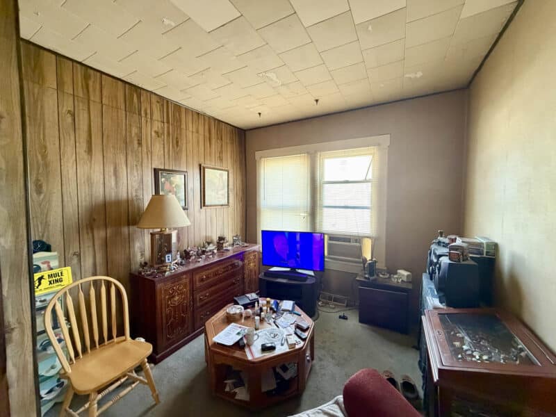 Living room with wood-paneled walls, drop ceiling, and front-facing windows at 8226 Fort Smallwood apartment unit