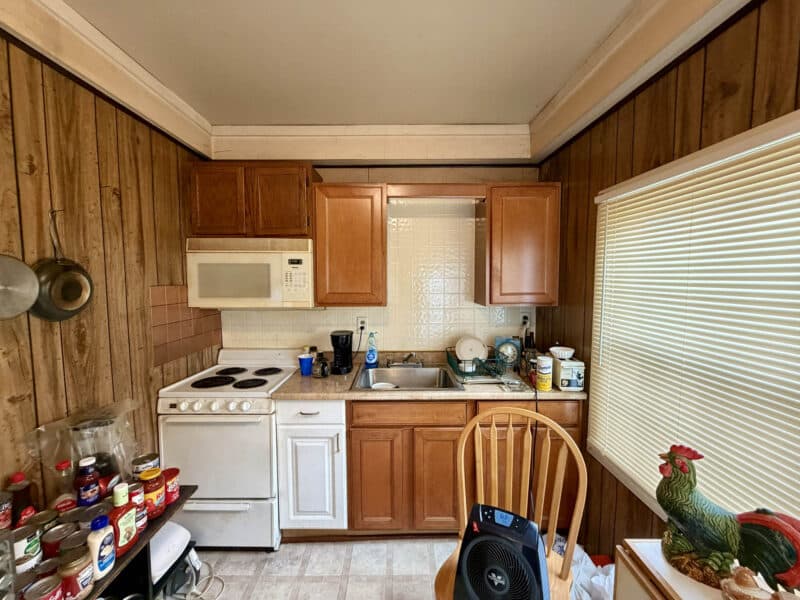 Kitchen view with electric stove, microwave, sink, and upper and lower cabinets in apartment unit