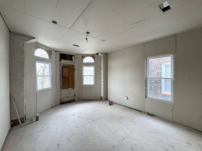 Front interior room with large windows and entry door in partially renovated building