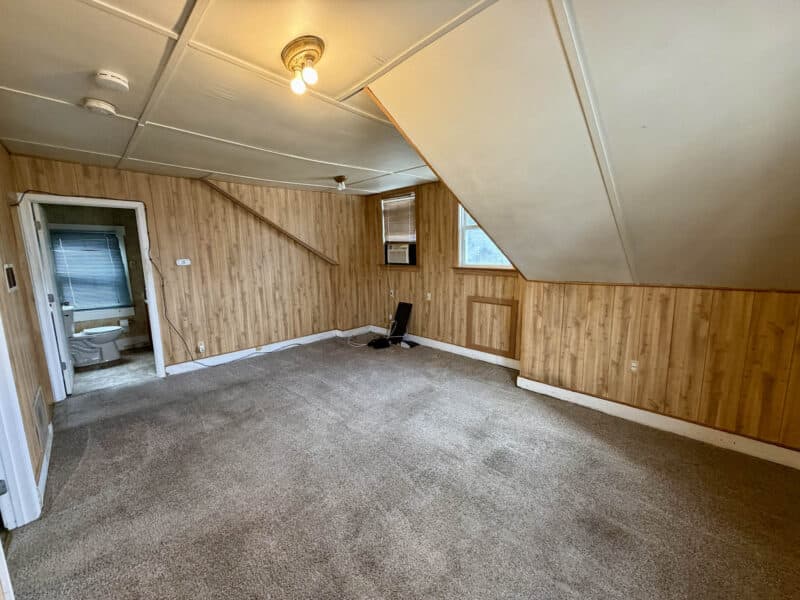 Upper-level living area with sloped ceilings, carpet flooring, and wood-paneled walls at 8226 Fort Smallwood apartment unit