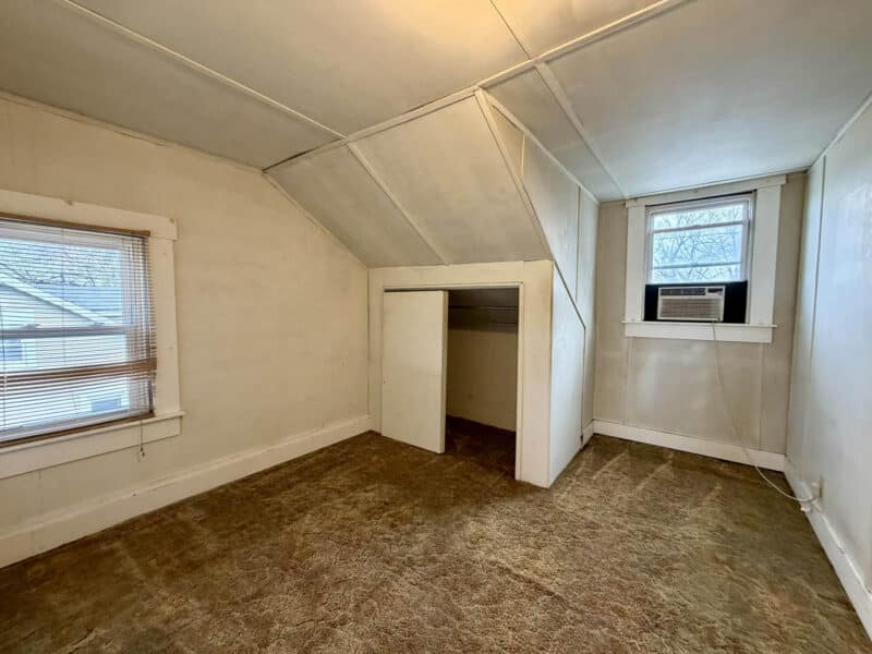 Bedroom area with sloped ceilings, window AC unit, and closet nook in 8226 Fort Smallwood apartment