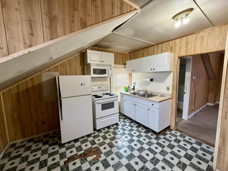 Kitchen with refrigerator, electric stove, sink, and vinyl flooring in upper-level apartment unit at 8226 Fort Smallwood