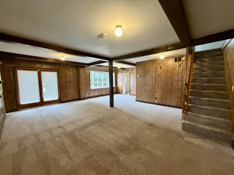 Large open room with staircase, wood paneling, and multiple windows in converted barn residence