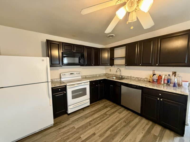 Kitchen with L-shaped layout, wood-look flooring, and overhead fan lighting in converted barn unit