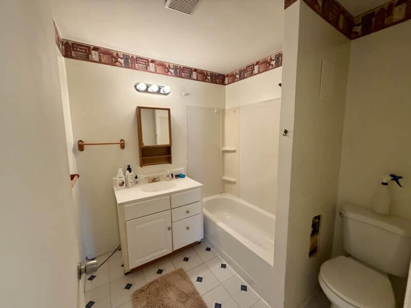 Bathroom with vanity, toilet, and tub shower combination in converted barn unit at 8226 Fort Smallwood