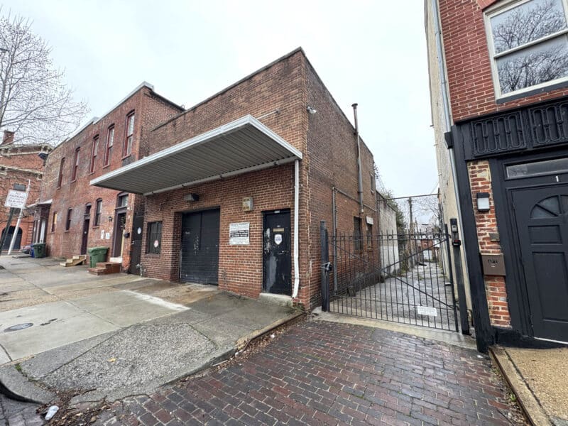 Angled exterior view of warehouse with gated alley access at 1205-1207 Hollins Street Baltimore