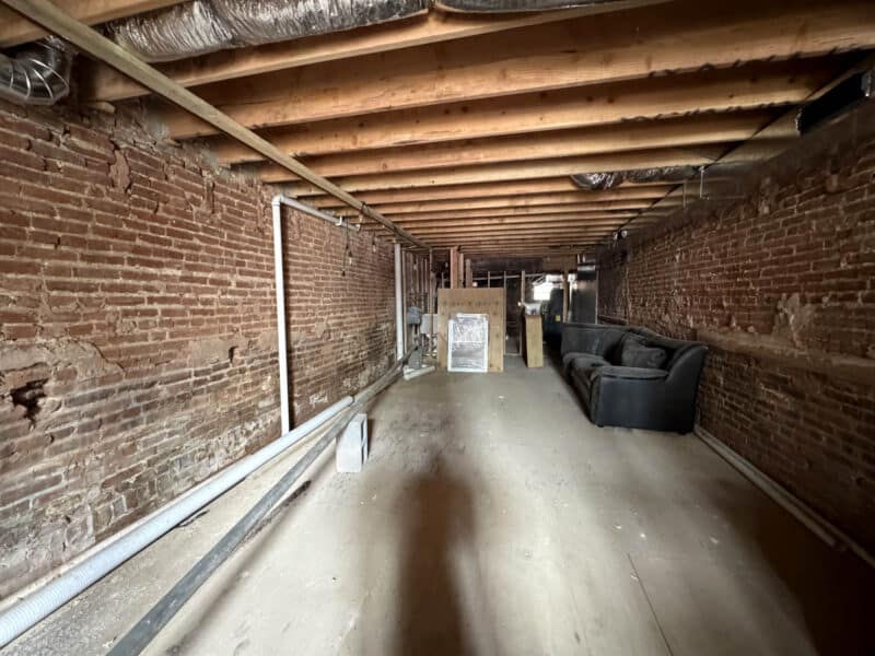 Lower level commercial space with exposed brick walls and open layout ready for renovation