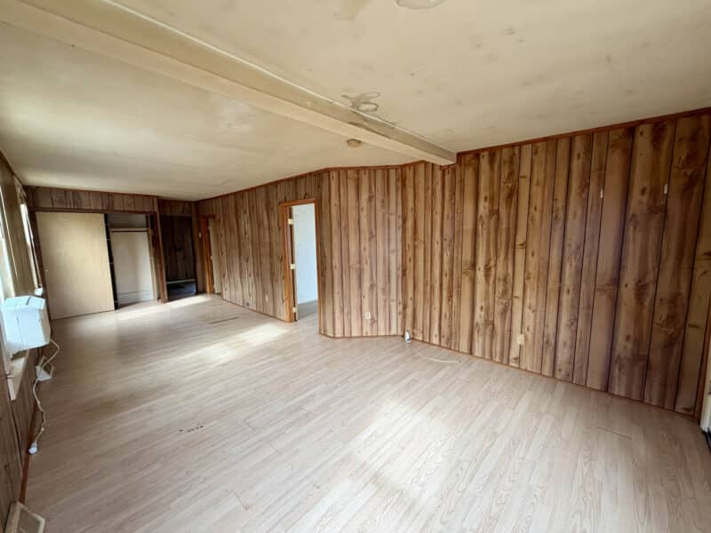 Interior living area with wood-paneled walls, open layout, and laminate flooring at 8224 Fort Smallwood Road