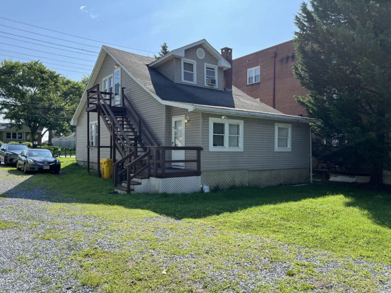 Side exterior of apartment building with elevated deck, exterior staircase, and yard area at 8226 Fort Smallwood