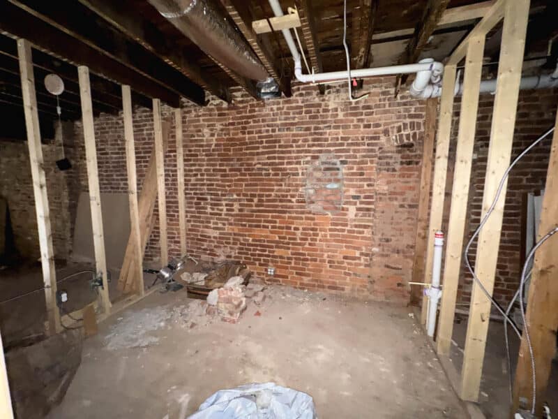 Framed commercial interior space with exposed brick and ductwork ready for buildout
