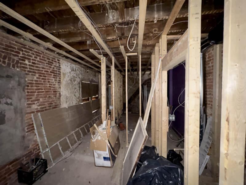 Commercial interior under renovation with framing, wiring, and construction materials visible