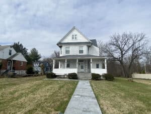 Front view of three-story detached apartment building with covered porch