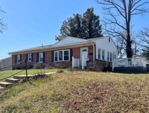 Front exterior brick and siding ranch home with elevated yard and composite deck in New Carrollton