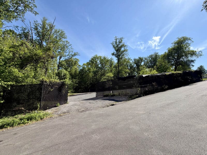 Chain-link fenced entrance to the paved industrial storage yard at 1220 Gloria Avenue in Linthicum Heights.