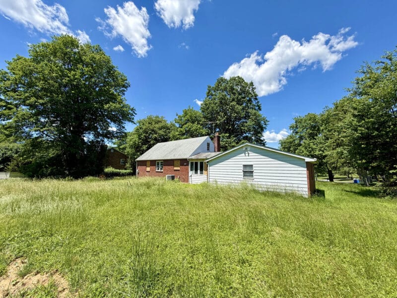 Side and rear exterior view of brick home with expansive yard and mature trees in Evergreen Heights.