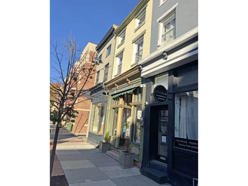 Angled sidewalk view of the storefronts along South Charles Street in the Federal Hill Main Street district of Baltimore.