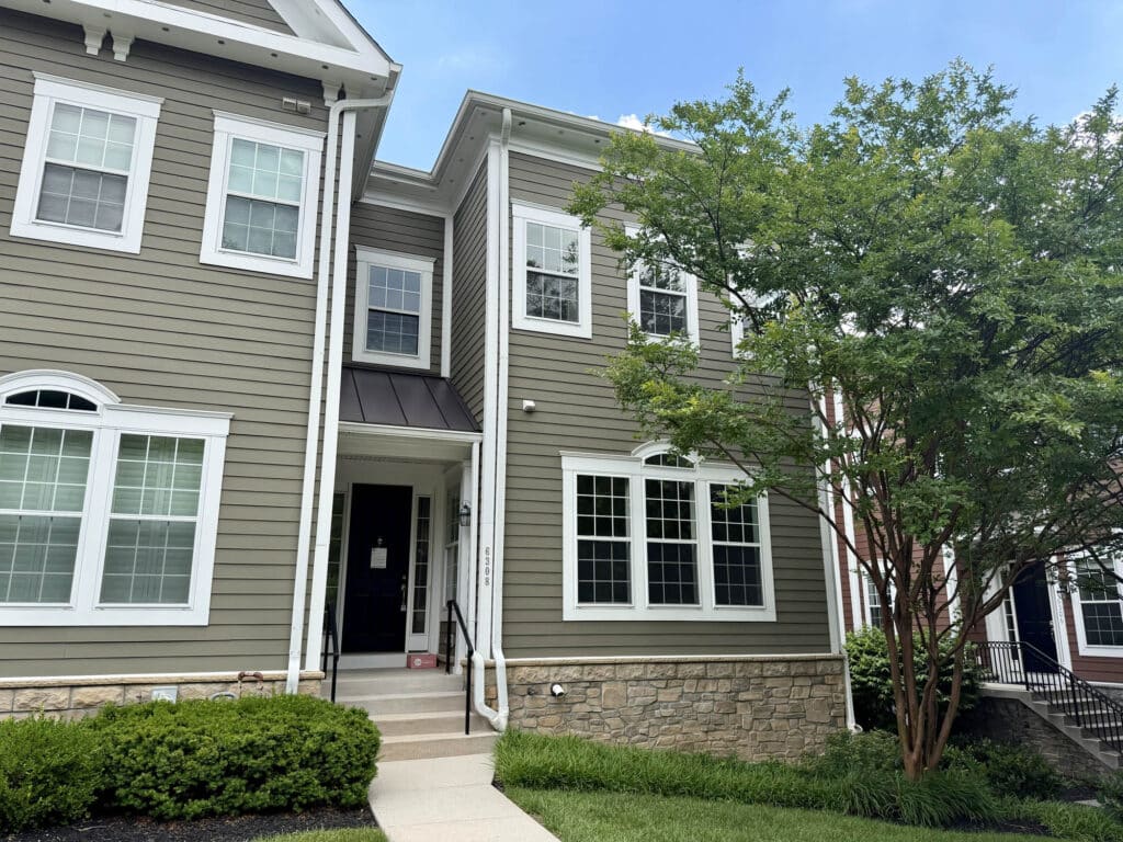 Front exterior of 6308 Canter Way in the Woodbrook on Charles Condominium community featuring attractive architecture, landscaped grounds and end-of-group townhouse design.