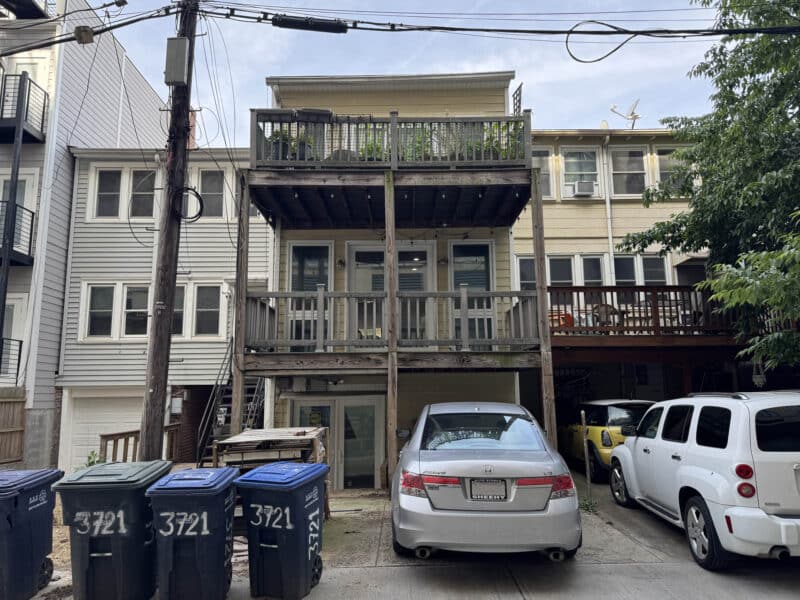 Rear exterior of apartment building with alley access, off-street parking, and rear decks.