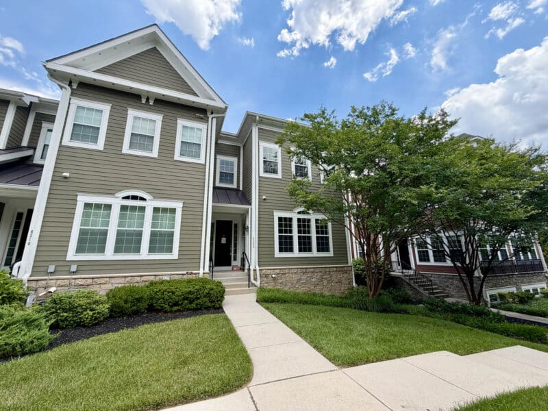 Front exterior of 6308 Canter Way in the Woodbrook on Charles Condominium community featuring attractive architecture, landscaped grounds and end-of-group townhouse design.