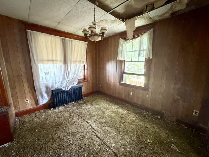 Dining room with wood-paneled walls and damaged ceiling in Dundalk renovation townhome