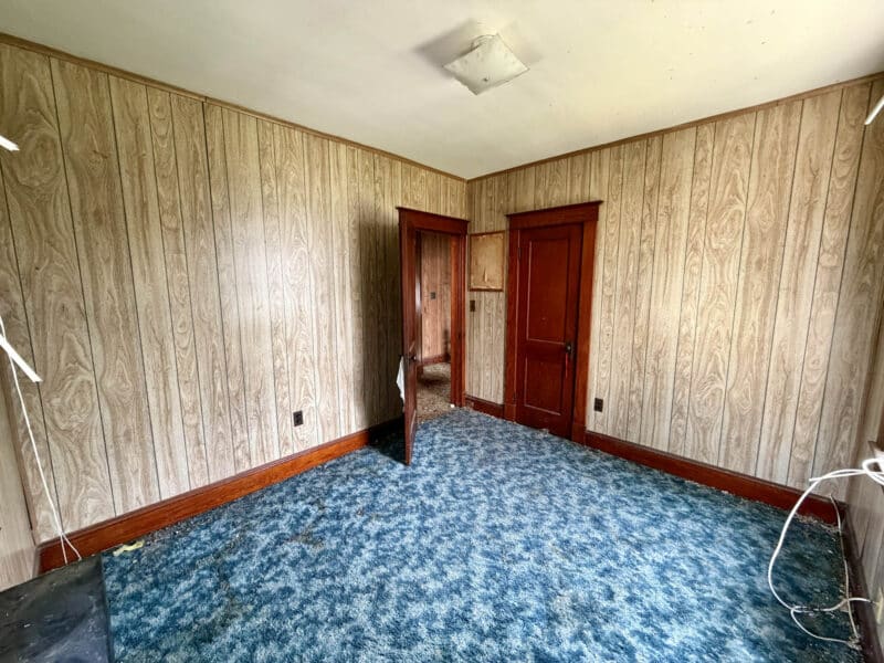Bedroom with carpet flooring and wood-paneled walls in Dundalk townhome