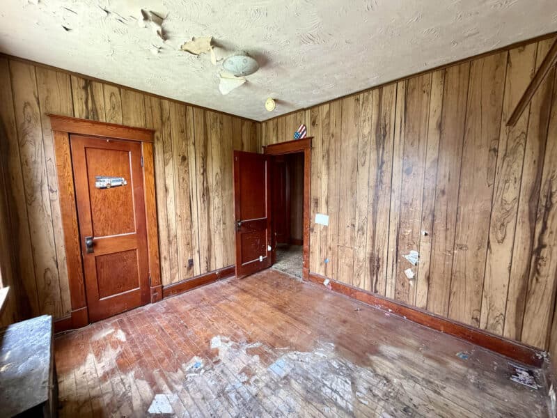 Alternate bedroom view showing hardwood flooring and damaged ceiling in Dundalk renovation home