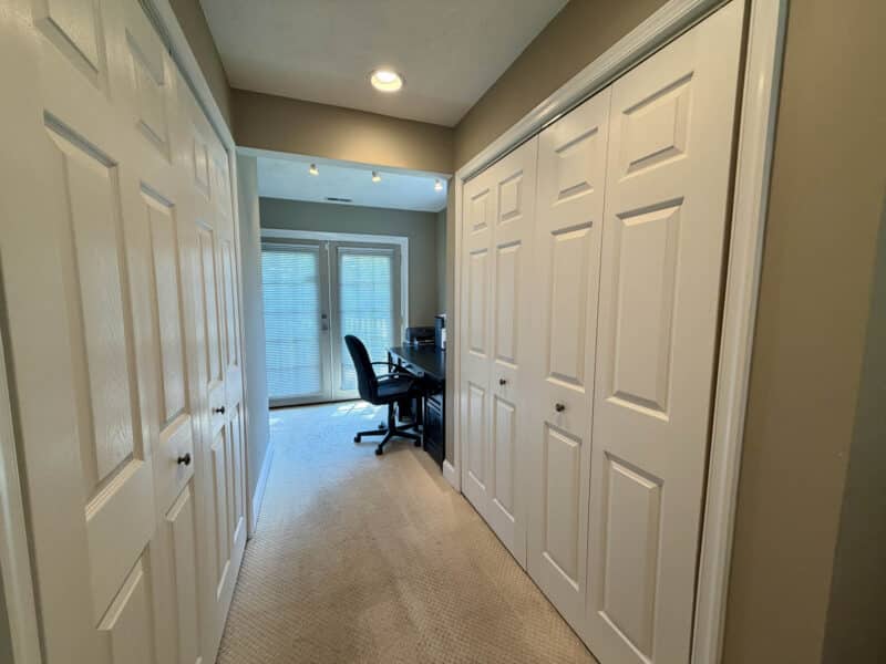 Interior hallway with multiple closets leading to home office with French doors to exterior.