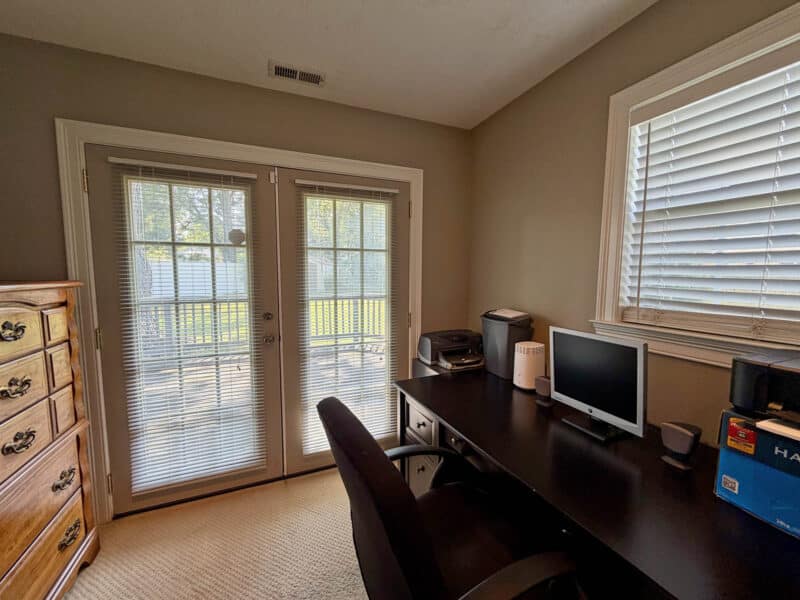 Home office with carpet flooring, window and French doors providing access to the backyard.