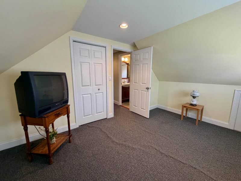 Finished upper-level bedroom with carpeting, closet, recessed lighting and sloped ceilings.