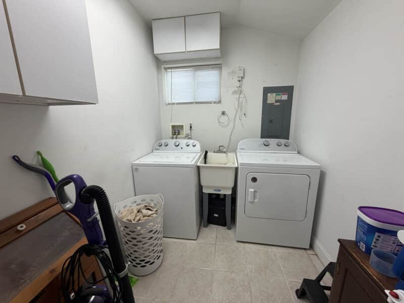 Laundry and utility room with washer, dryer, utility sink, storage cabinets and electrical panel.