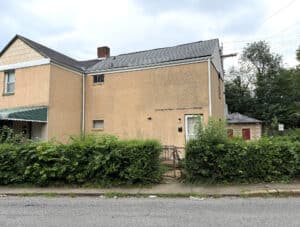 Side exterior of 4909 Pembridge Avenue, a semi-detached stucco home in Central Park Heights, Baltimore