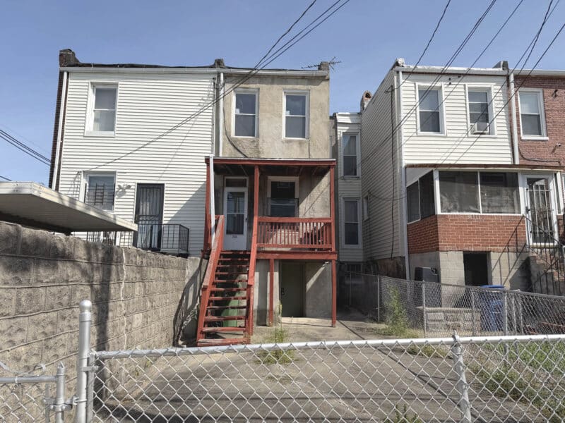 Rear exterior of 2545 W. Lafayette Avenue showing the wood porch, fenced yard and rear entrance.
