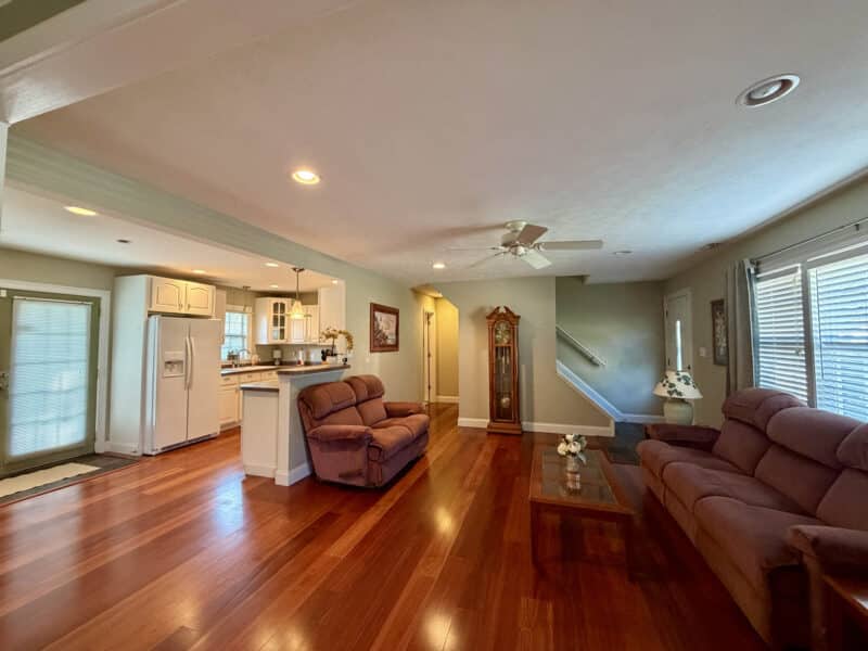 Open living room and kitchen with hardwood floors, recessed lighting, breakfast bar and white cabinetry.