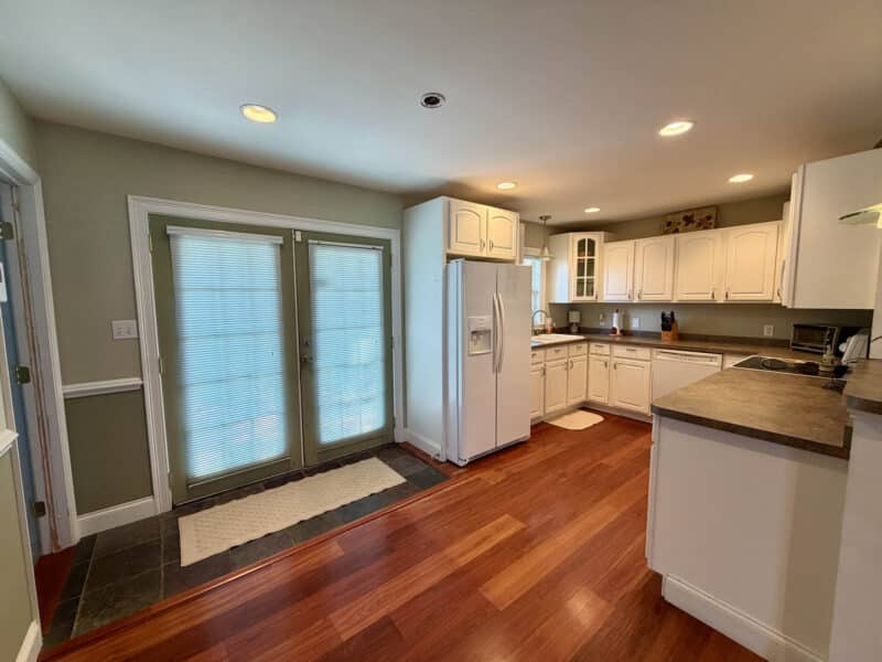 Kitchen with white cabinets, hardwood floors, recessed lighting, appliances and French doors to exterior.