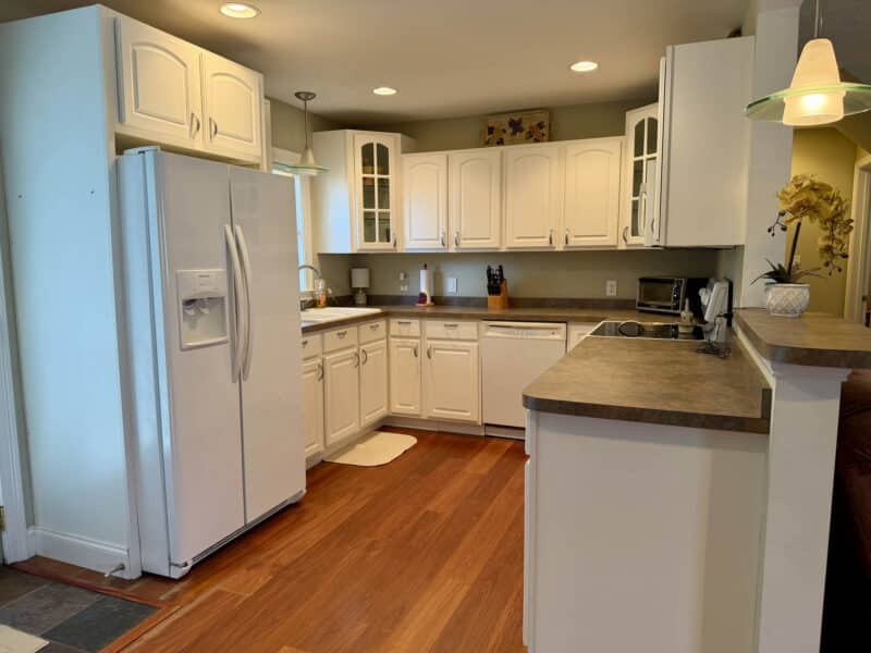 Kitchen with white cabinetry, breakfast counter, electric cooktop, dishwasher and side-by-side refrigerator.