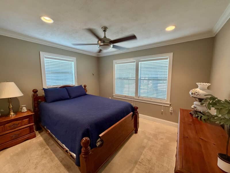 Bedroom with carpeting, ceiling fan, crown molding and multiple windows.