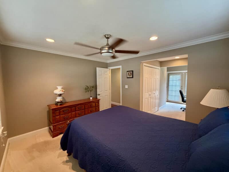 Bedroom with carpet flooring, ceiling fan, recessed lighting and adjoining hallway with closet storage.