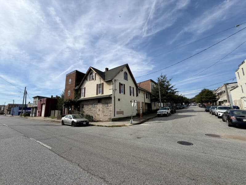 Wide street view of 4900 Curtis Avenue showing the corner mixed-use building and surrounding Curtis Bay neighborhood in Baltimore City.