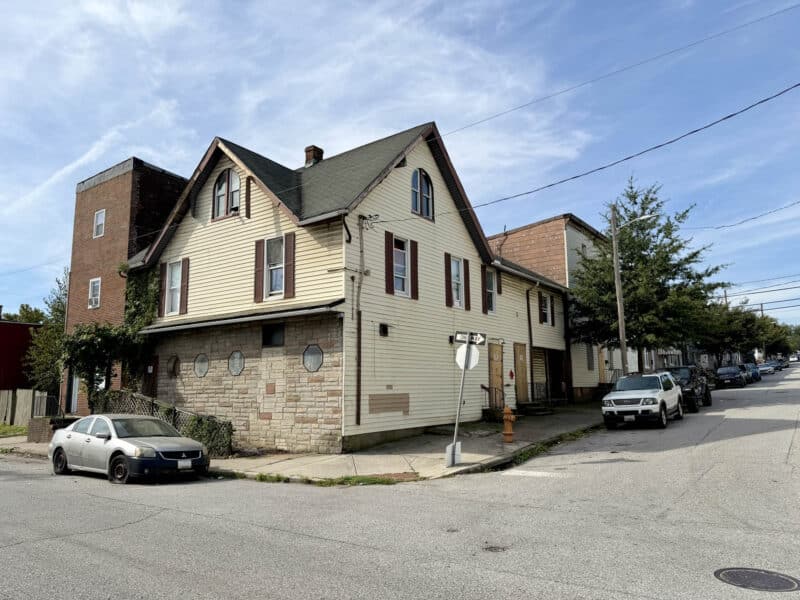 Corner mixed-use building at 4900 Curtis Avenue in Curtis Bay, Baltimore, featuring vinyl siding, stone facade, and gabled roof.