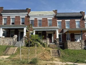 Front exterior of 2818 Presstman Street, a two-story porchfront brick townhome in West Baltimore