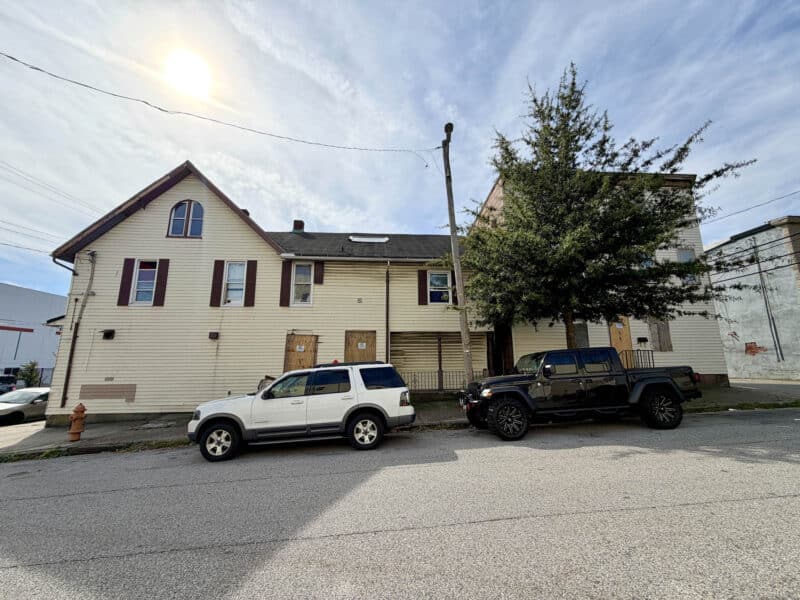 Cherry Street elevation of 4900 Curtis Avenue showing vinyl siding, multiple entrances, second-story windows, and gabled roof.