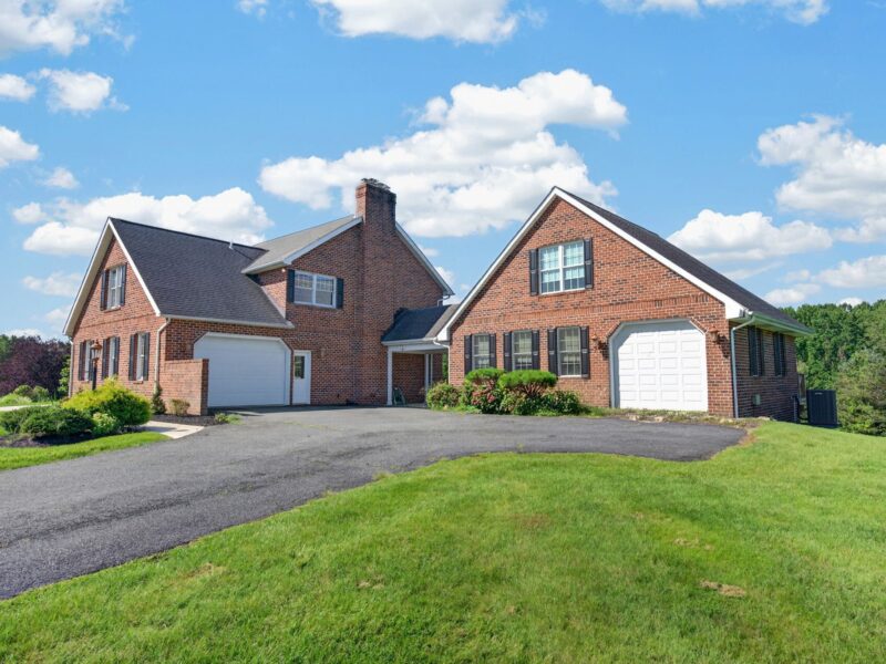 Side exterior view of brick residence with multiple garages and paved driveway