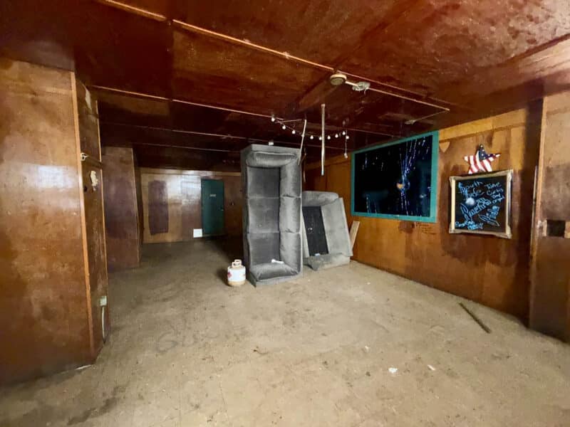 Former tavern seating area at 4900 Curtis Avenue in Baltimore with wood-paneled walls, ceiling panels, and vacant interior space.