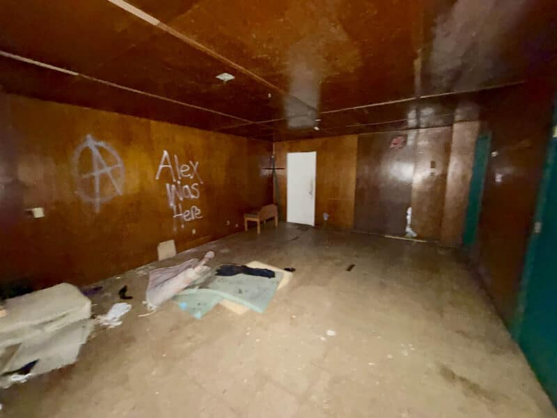 Vacant room within former tavern at 4900 Curtis Avenue featuring wood-paneled walls, graffiti, and worn flooring.